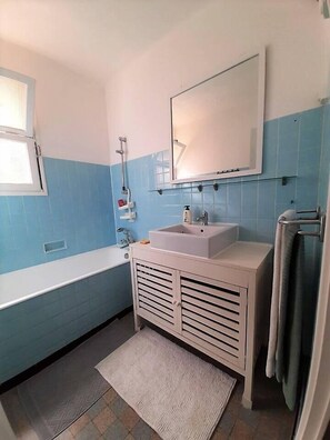 Un baño con lavamanos blanco, un espejo y una bañera.