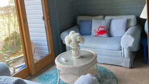 A living room with a ceiling fan, a couch, a round coffee table with a vase, and a view through a glass door. - 5 block walk to the boardwalk at  Stockley (Rehoboth Beach)
