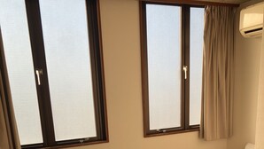 A hotel room with a single bed, a bedside table with a phone, and two windows with curtains. - Hotel Tsuchiura Kandatsu Hills (Tsuchiura)