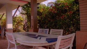 An outdoor patio with a round table and white chairs, surrounded by lush greenery and a brick wall. - Big Comfortable Villa (Banglamung)
