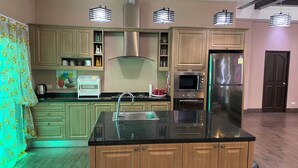 A modern kitchen with wooden cabinets, a stainless steel refrigerator, a microwave, and a sink. - Big Comfortable Villa (Banglamung)