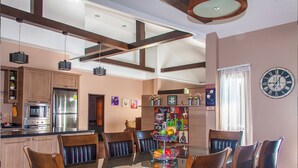 A modern kitchen with stainless steel appliances, a dining area with a glass table and leather chairs, and a decorative wall with artwork. - Big Comfortable Villa (Banglamung)