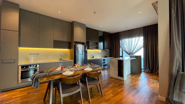 Una cocina moderna con comedor, piso de madera y vistas de la ciudad a través de amplios ventanales.