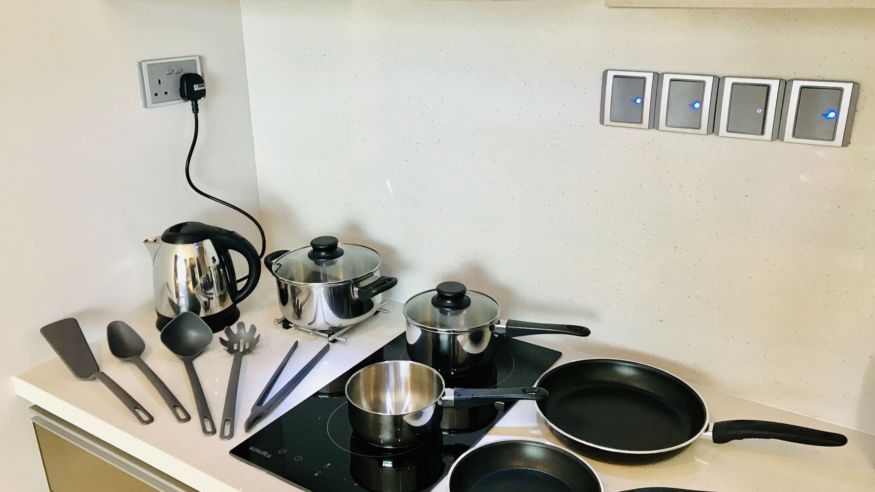 Una cocina con estufa, ollas, sartenes y utensilios de cocina.