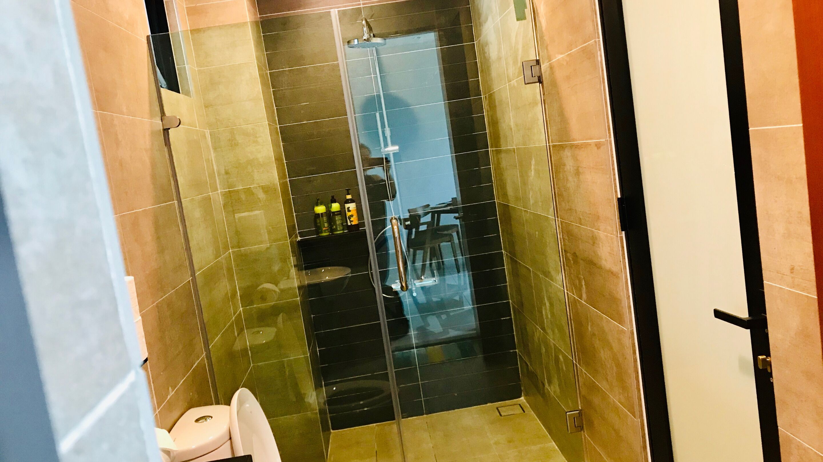 Un baño pequeño con azulejos, ducha, inodoro y puerta de vidrio.