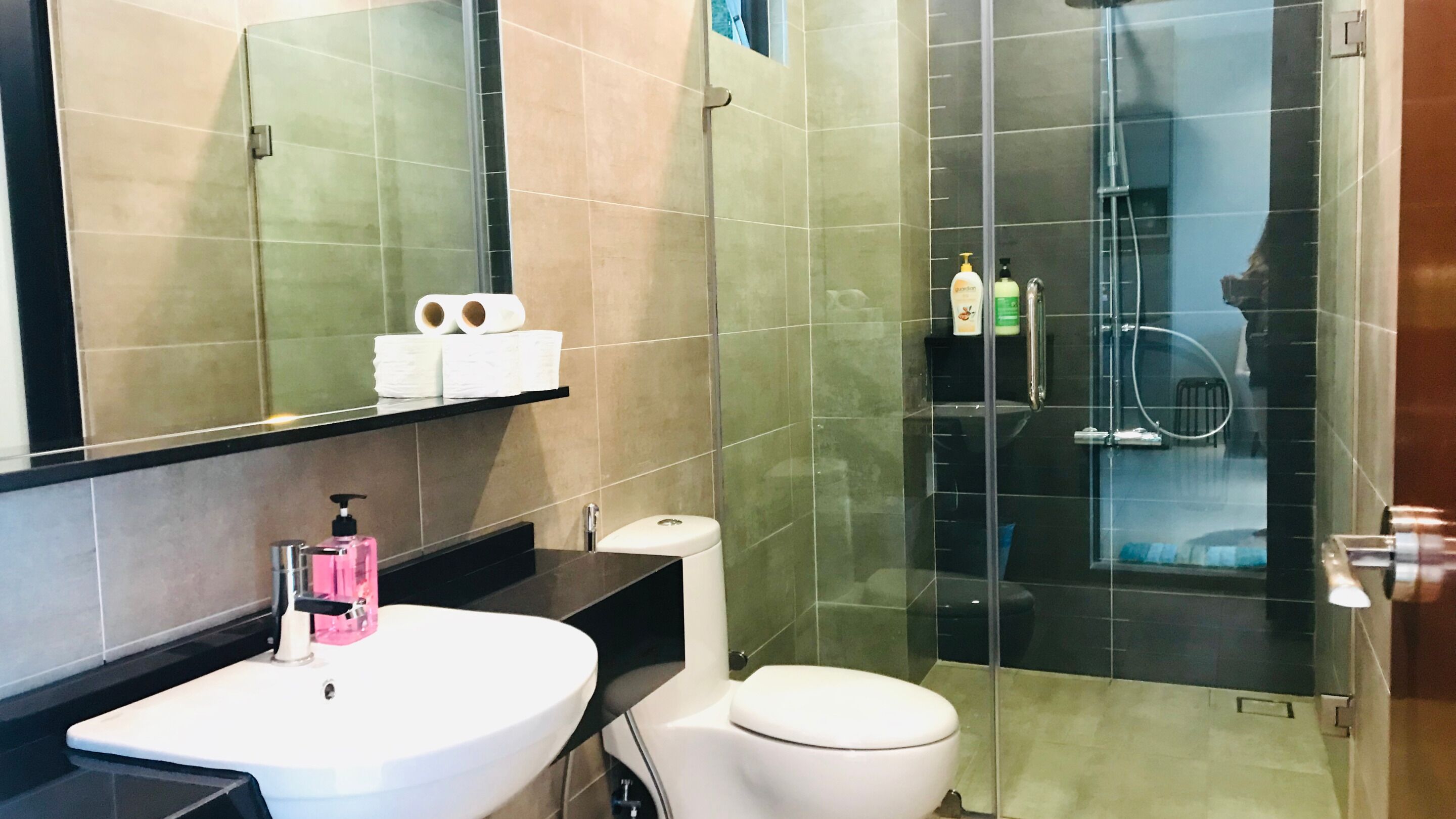 A modern bathroom with a white sink, toilet, and glass-enclosed shower.