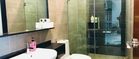 A modern bathroom with a white sink, toilet, and glass-enclosed shower.