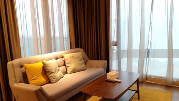 Habitación de hotel con sofá, una mesa de centro y una ventana con cortinas.