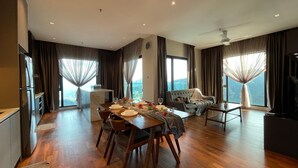 Una sala de estar moderna con comedor, ventanas amplias con cortinas, un sofá y una televisión.
