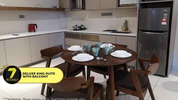 Una cocina moderna con una mesa de comedor para cuatro personas, un refrigerador y una tetera roja sobre la encimera.
