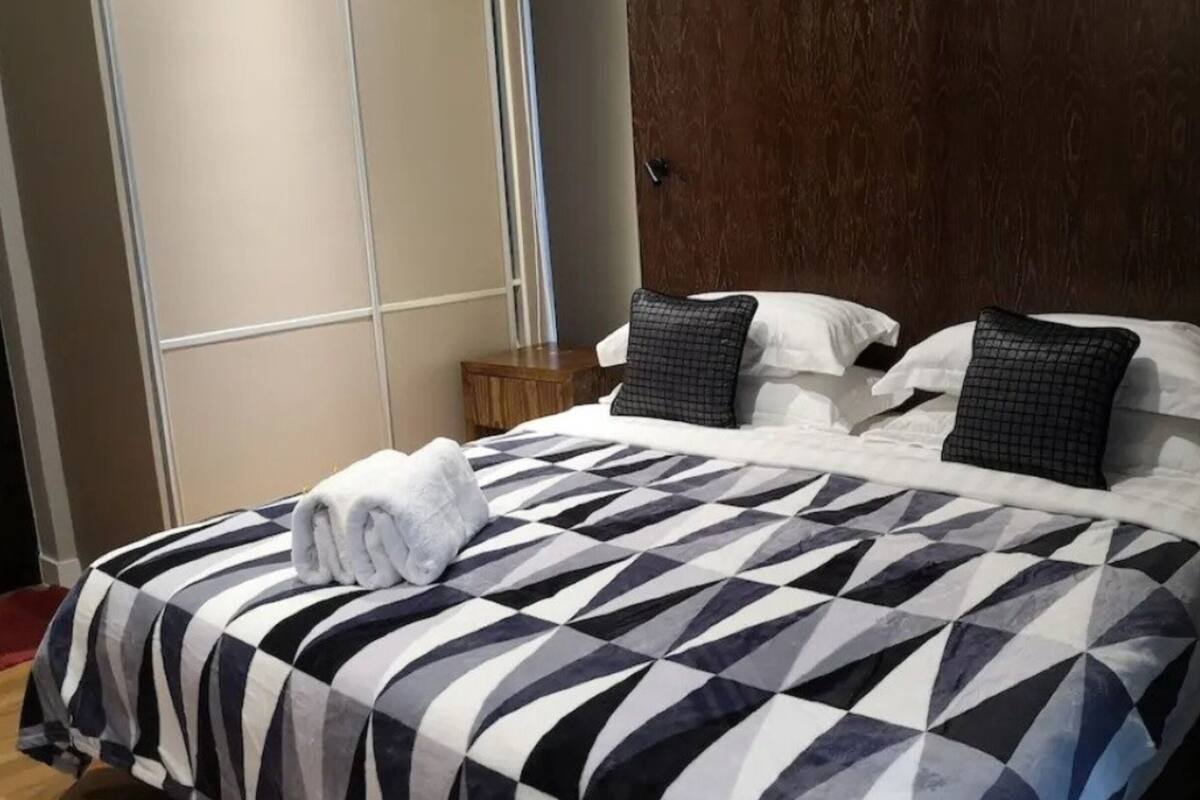 Ein Hotelzimmer mit einem Bett, einem hölzernen Kopfteil und einem Nachttisch mit Lampe.