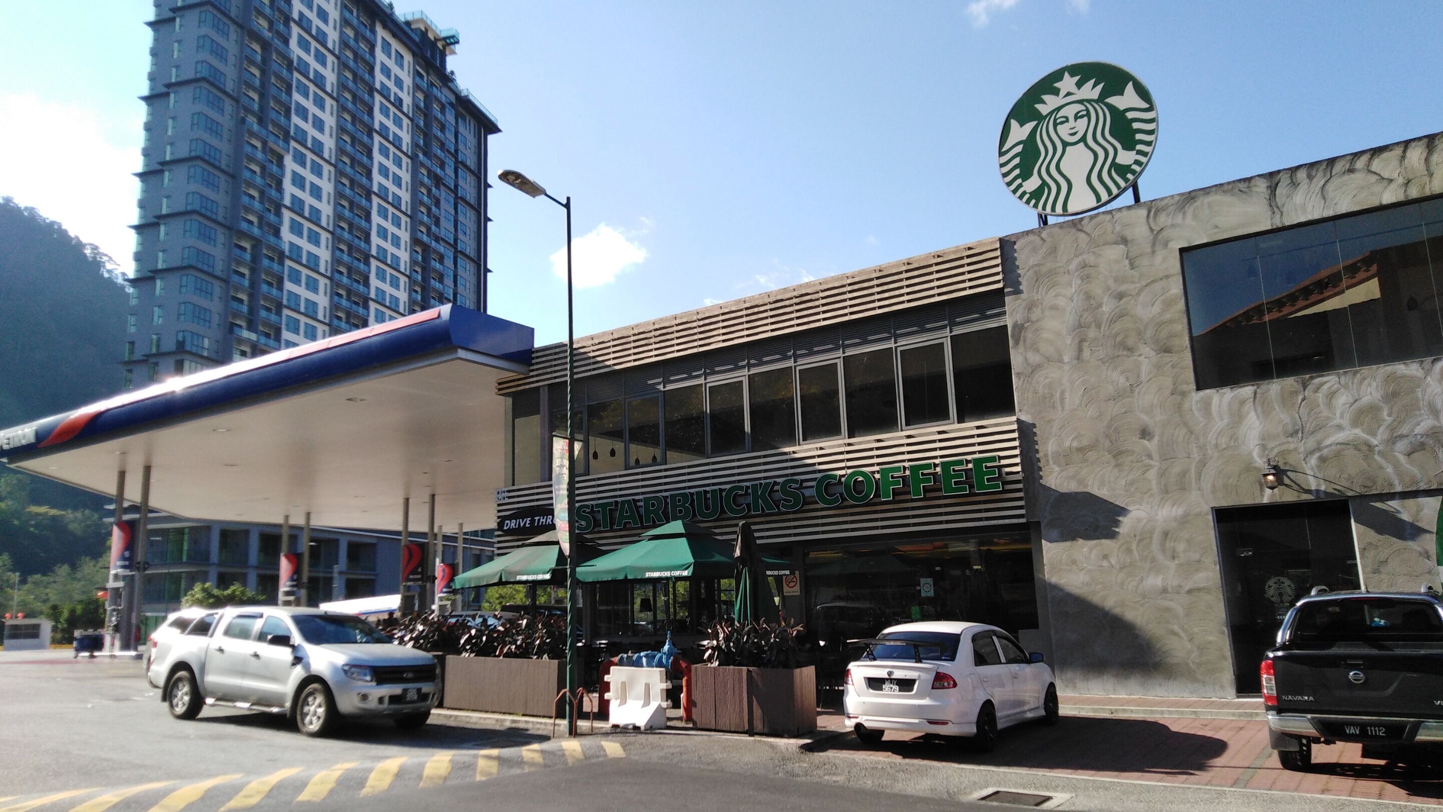 A Starbucks Coffee store with a modern facade, located at a street corner with cars parked in front.