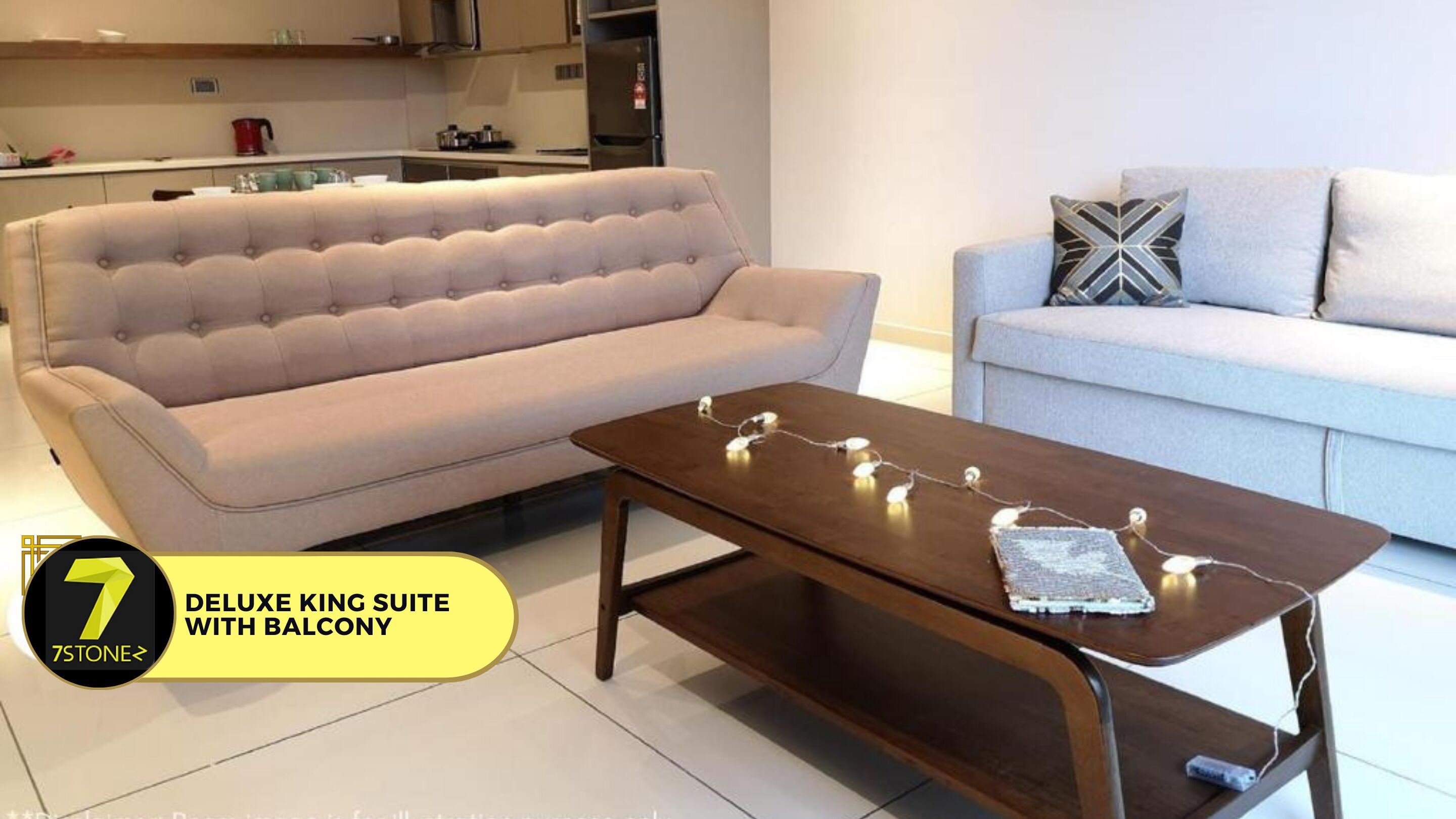 Ein Wohnzimmer mit einem beigen Sofa, einem hellgrauen Sofa und einem Couchtisch aus Holz mit Lichterkette.
