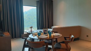 Un comedor con una mesa redonda, sillas y vistas a un bosque a través de un ventanal grande.