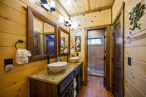 A wooden cabin bathroom with a large mirror, two sinks, and a shower area. - Jolly Roger Cabin | Pirate Ship Playground | Luxury Broken Bow Retreat (BROKEN BOW)