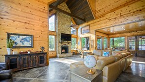 A spacious living room with a fireplace, leather sofa, and a large globe on a table. - Jolly Roger Cabin | Pirate Ship Playground | Luxury Broken Bow Retreat (BROKEN BOW)