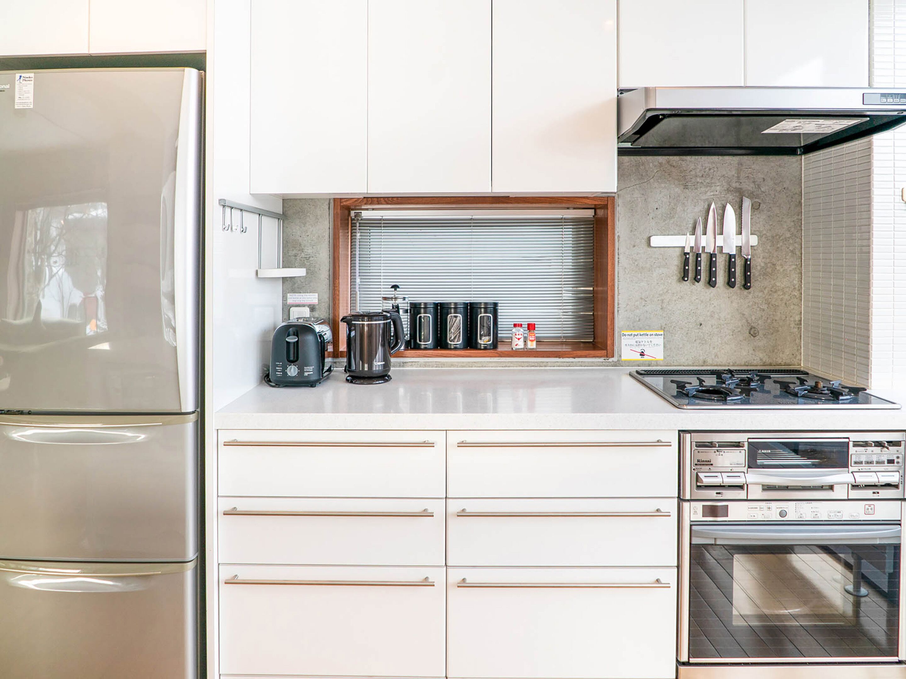 Une cuisine moderne équipée d’un réfrigérateur, d’un grille-pain, d’une bouilloire, d’une cuisinière, d’un four et d’un porte-couteaux.
