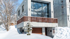 A modern building with a large glass window, a concrete facade, and a wooden balcony. - Yuuki Toride Chalet (Kutchan)