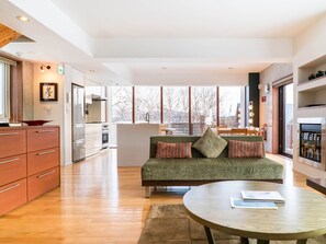 Relax in this inviting space with a central sofa, dining area, and fireplace, offering a view of the outdoors.