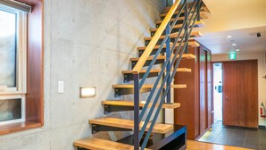 A staircase with wooden steps and metal railings, leading to a landing with a wooden door. - Yuuki Toride Chalet (Kutchan)