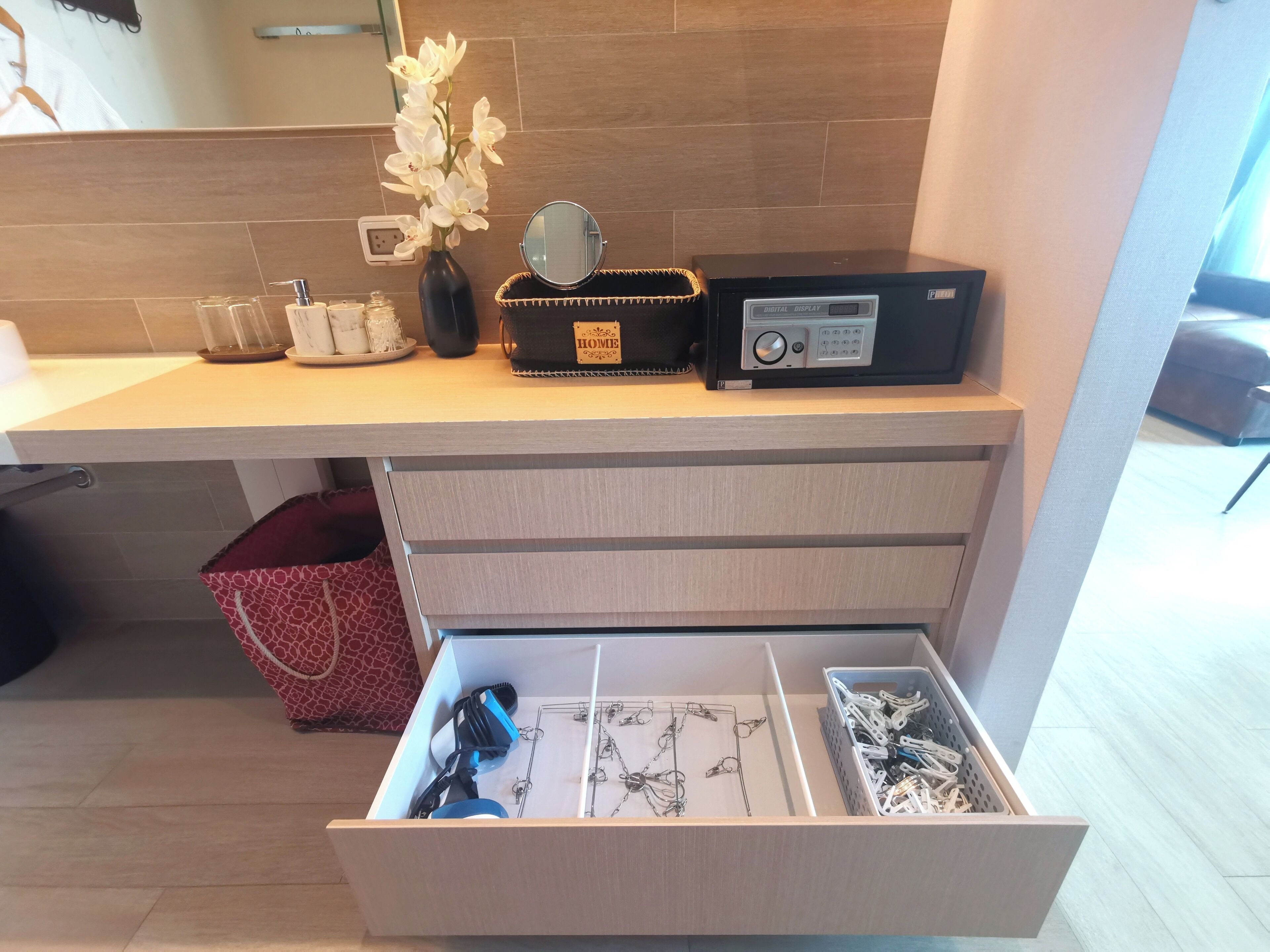 A modern kitchen with a wooden countertop, a digital display device, and a drawer with various utensils.
