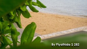 A beach with a boat in the distance and a plant in the foreground. - 456 Veranda Residence Pattaya Jomtien Sea View 1BR; Beachfront (Chonburi)
