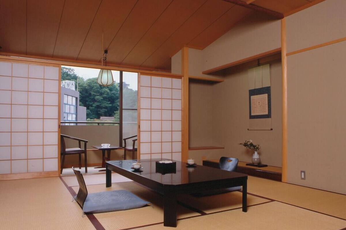 A traditional Japanese room with tatami flooring, a low table, and sliding doors.