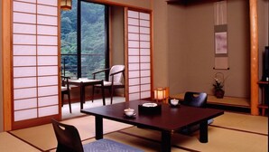 Une pièce de style japonais traditionnel, avec un sol recouvert de tatamis, une table basse avec des coussins et des portes coulissantes en papier de riz (shoji).
