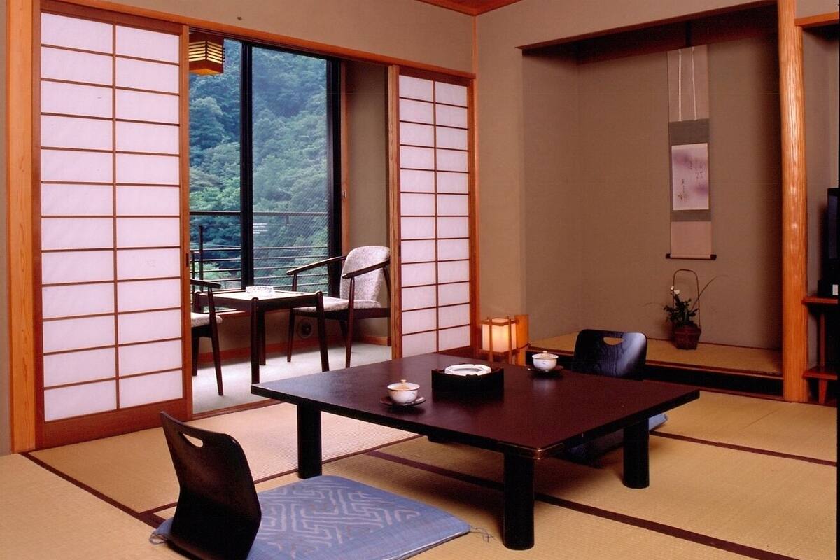 A traditional Japanese room with tatami flooring, a low table with cushions, and sliding shoji doors.