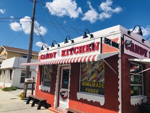 A candy store with a red and white facade, a sign reading "Candy Kitchen," and a window displaying "Homemade Fudge."
