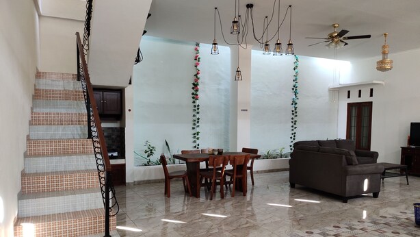 A spacious living area with a dining table, sofa, and staircase. - ZG Homestay Solo (Surakarta)