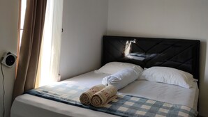 A hotel room with a bed, a window with curtains, and an air conditioning unit. - ZG Homestay Solo (Surakarta)