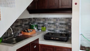A compact kitchen with dark wooden cabinets, a tiled backsplash, and a gas stove. - ZG Homestay Solo (Surakarta)