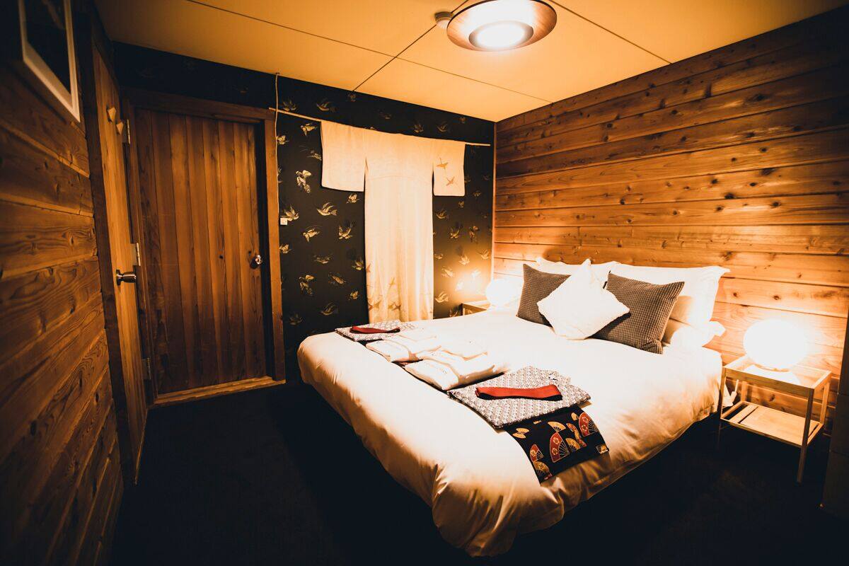 Une chambre confortable avec une tête de lit en bois, un lit bien fait avec des oreillers et une couverture, et une lampe de chevet.