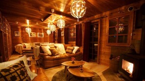 Un intérieur chaleureux de chalet en bois, avec une cheminée, des canapés en cuir et une décoration en bois.