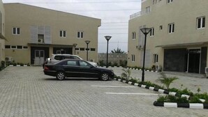 A paved driveway leading to a building with a car parked in front. - Newcastle Hotel (Lagos)