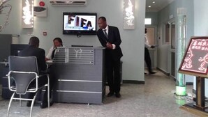 A hotel reception area with a reception desk, a television mounted on the wall, and a signboard with text. - Newcastle Hotel (Lagos)