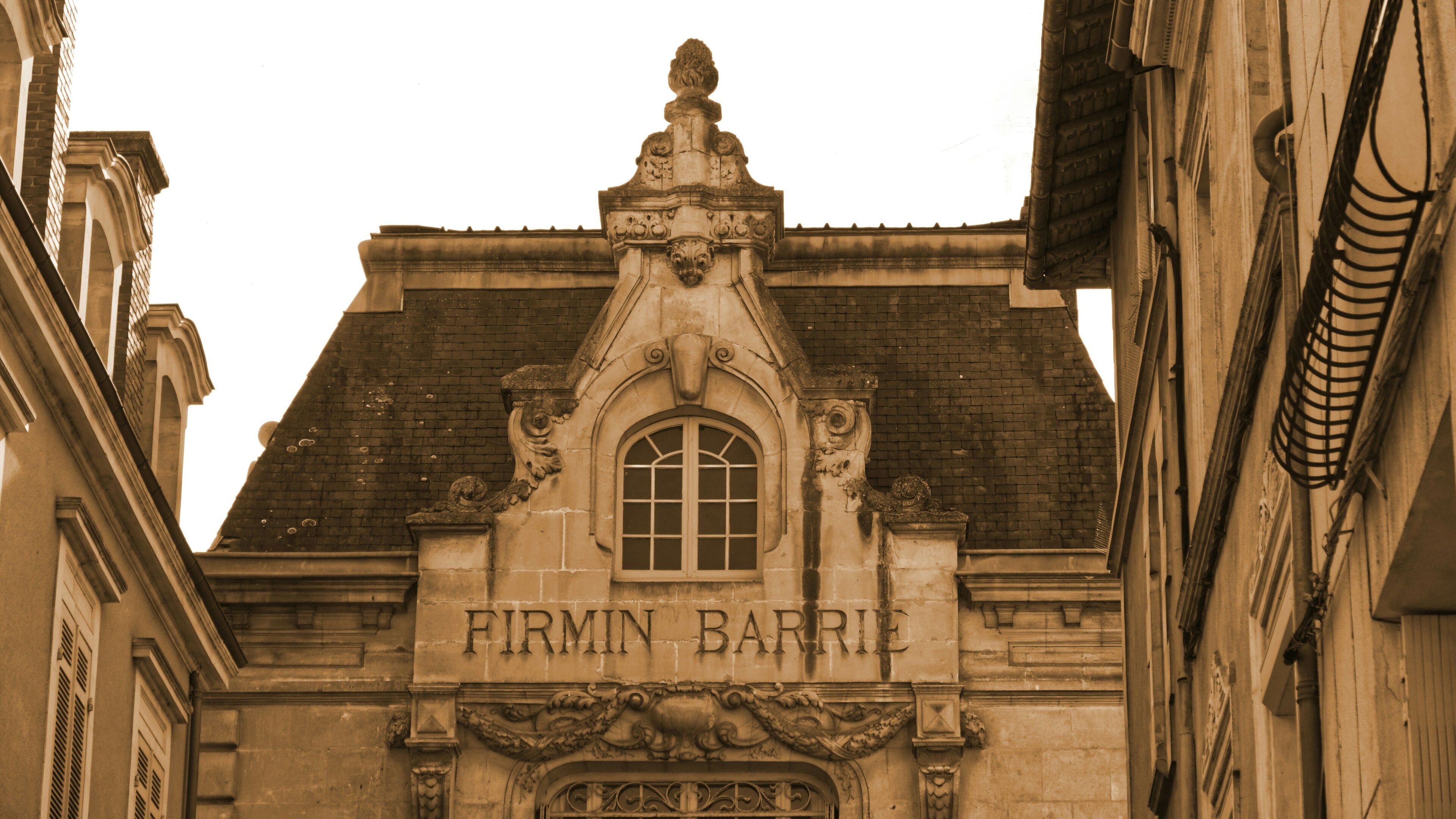 A building facade with the inscription 'FIRMIN BARRI' and ornate architectural details.