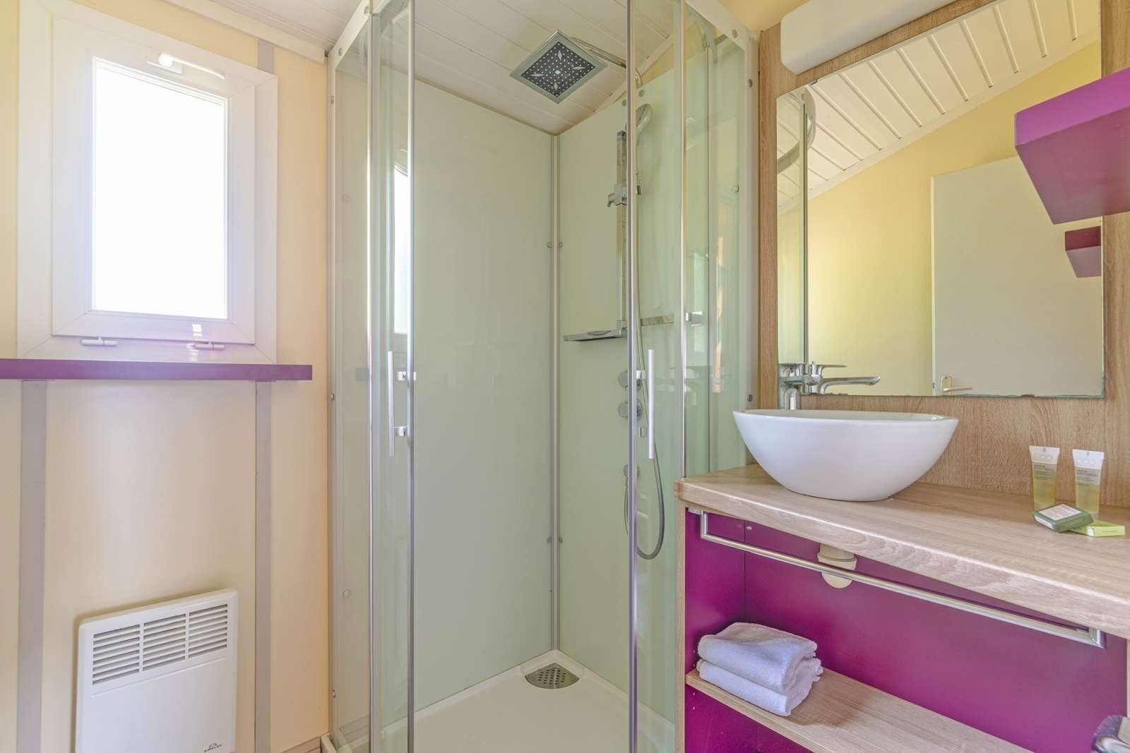Een moderne badkamer met een douchecabine van glas, een witte wastafel en een meubel met spiegel.