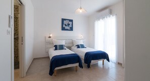 Un dormitorio con dos camas, cabecero blanco y un tapiz azul.