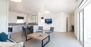 A modern living space with a kitchen, dining area, and a large window.