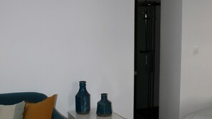 A room with a hanging lamp, a blue vase, and a small candle on a table.