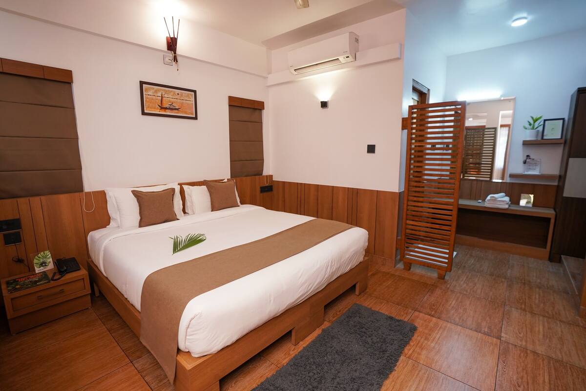 Una habitación de hotel moderna con una cama de madera, una mesita de noche, un escritorio, un espejo y un pequeño estante con una planta.
