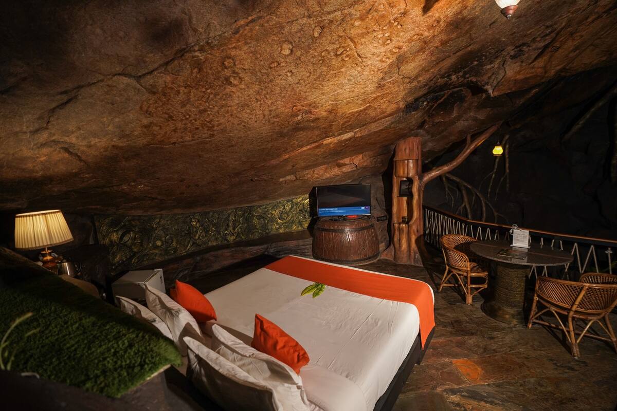 Una habitación acogedora, con forma de cueva, que incluye una cama, una mesita y sillas.