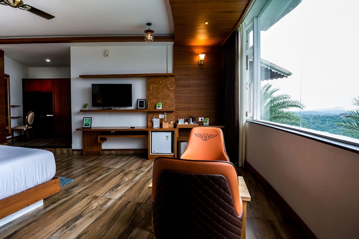 Habitación de hotel con cama, escritorio con computadora, televisión y vistas al exterior.