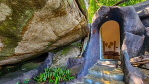 A stone staircase leading to a room with a bed and a wall decorated with circular objects. - Mount Xanadu (Sulthan Bathery)