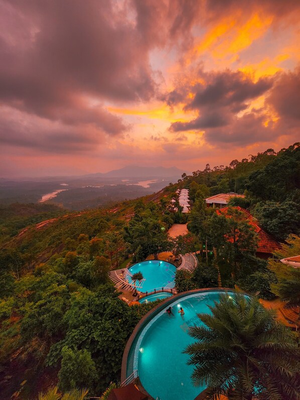 Una piscina al aire libre, una piscina infinita, sombrillas