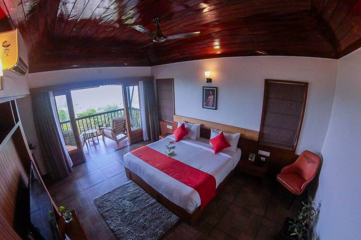 Un dormitorio con una cama grande, ventilador de techo, ventana y vistas al exterior.