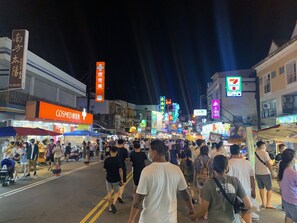 A busy street at night with various shops and a 7-Eleven store. - Kenting Jinjin Music Inn (Hengchun)