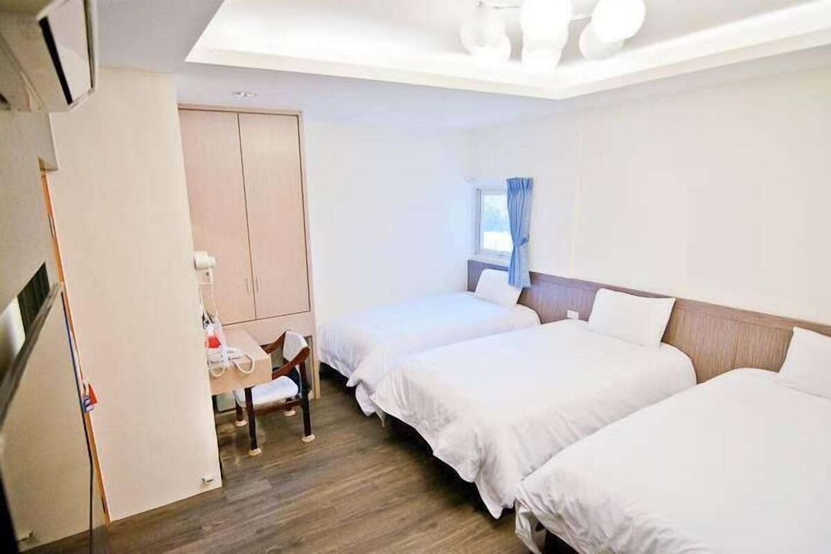A hotel room with two beds, a desk, and a wardrobe.